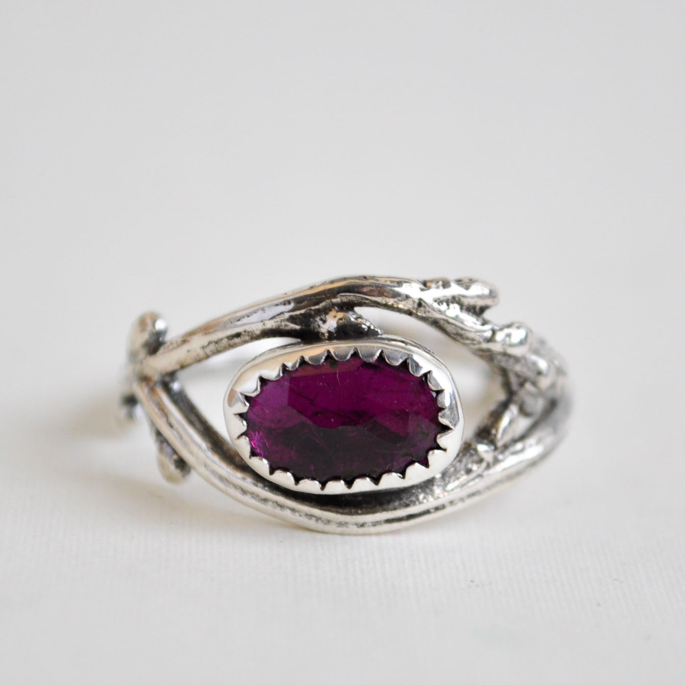 Silver ring with a purple gemstone on a white background
