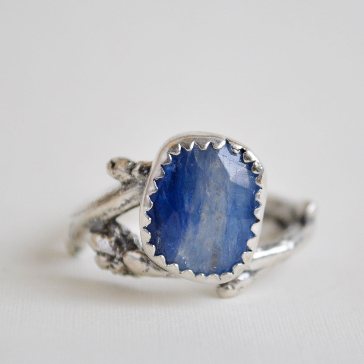Silver ring with a blue stone on a light gray background
