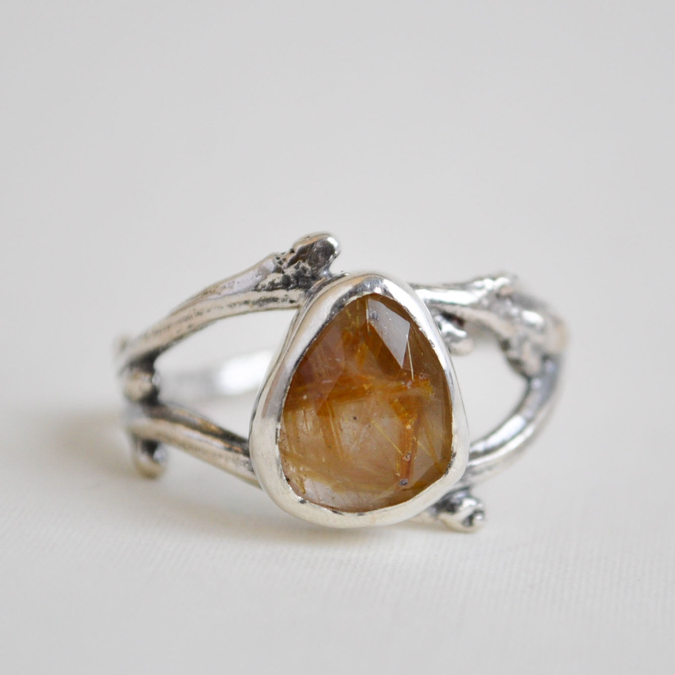 Silver ring with a large brown stone on a light gray background