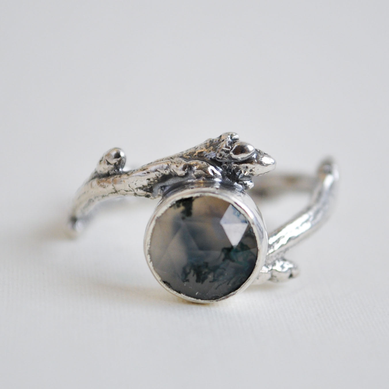 Silver ring with a dark stone on a light gray background