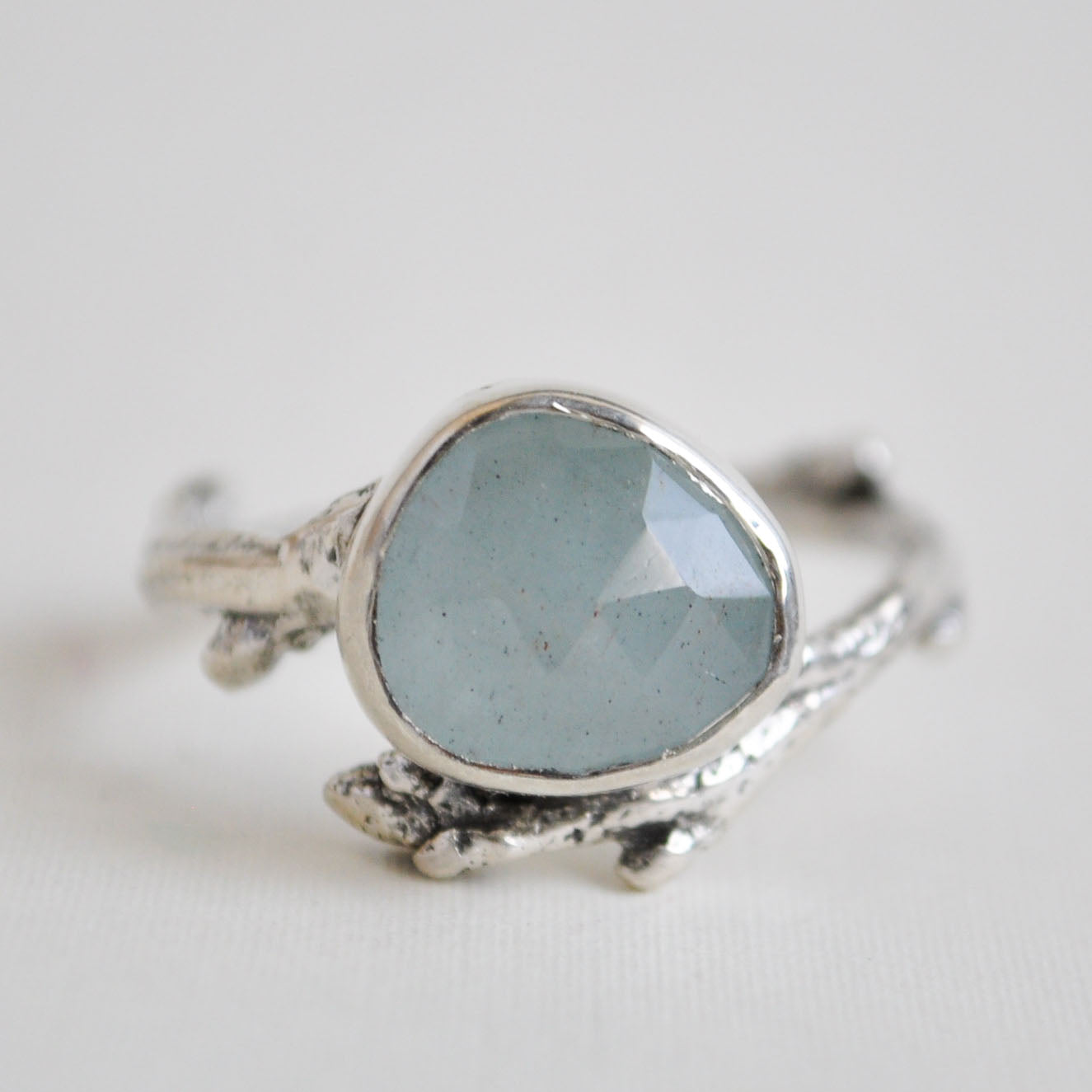 Silver ring with a light blue gemstone on a white background