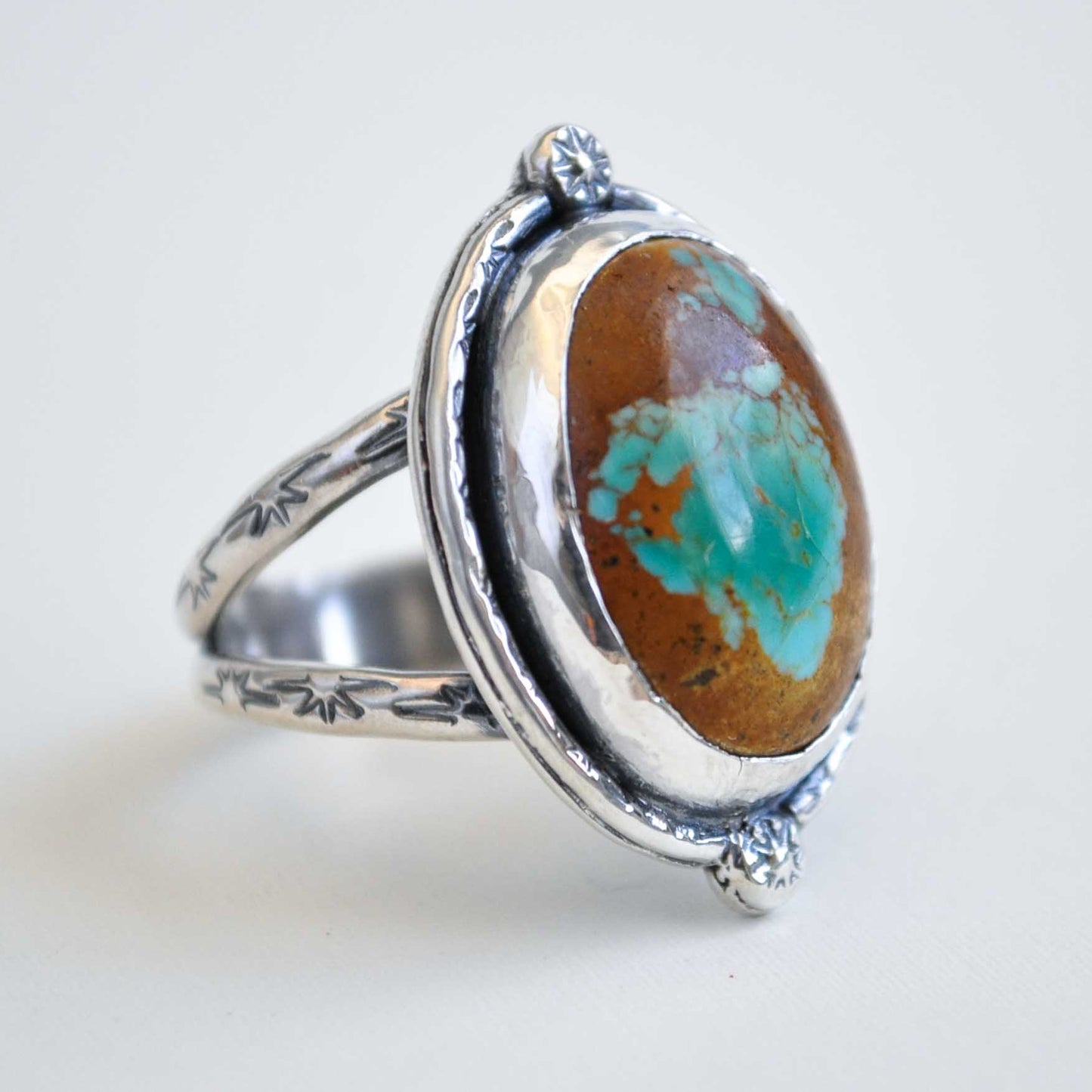 Silver ring with a large oval stone featuring brown and turquoise colors on a white background