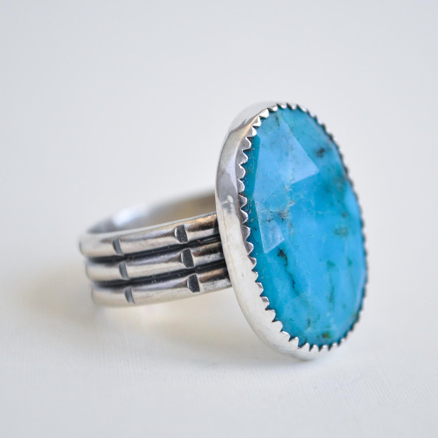 Silver ring with a large turquoise stone on a light background