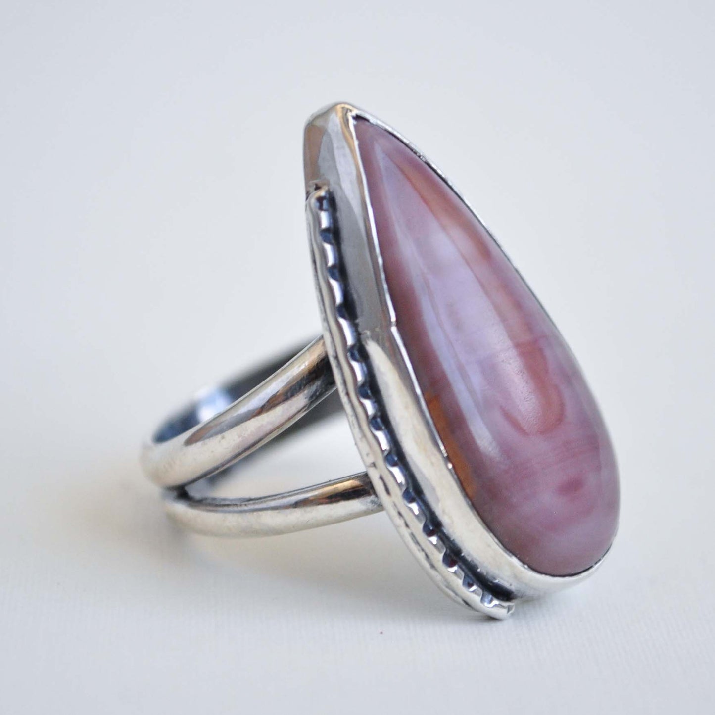 Silver ring with a large purple stone on a light gray background