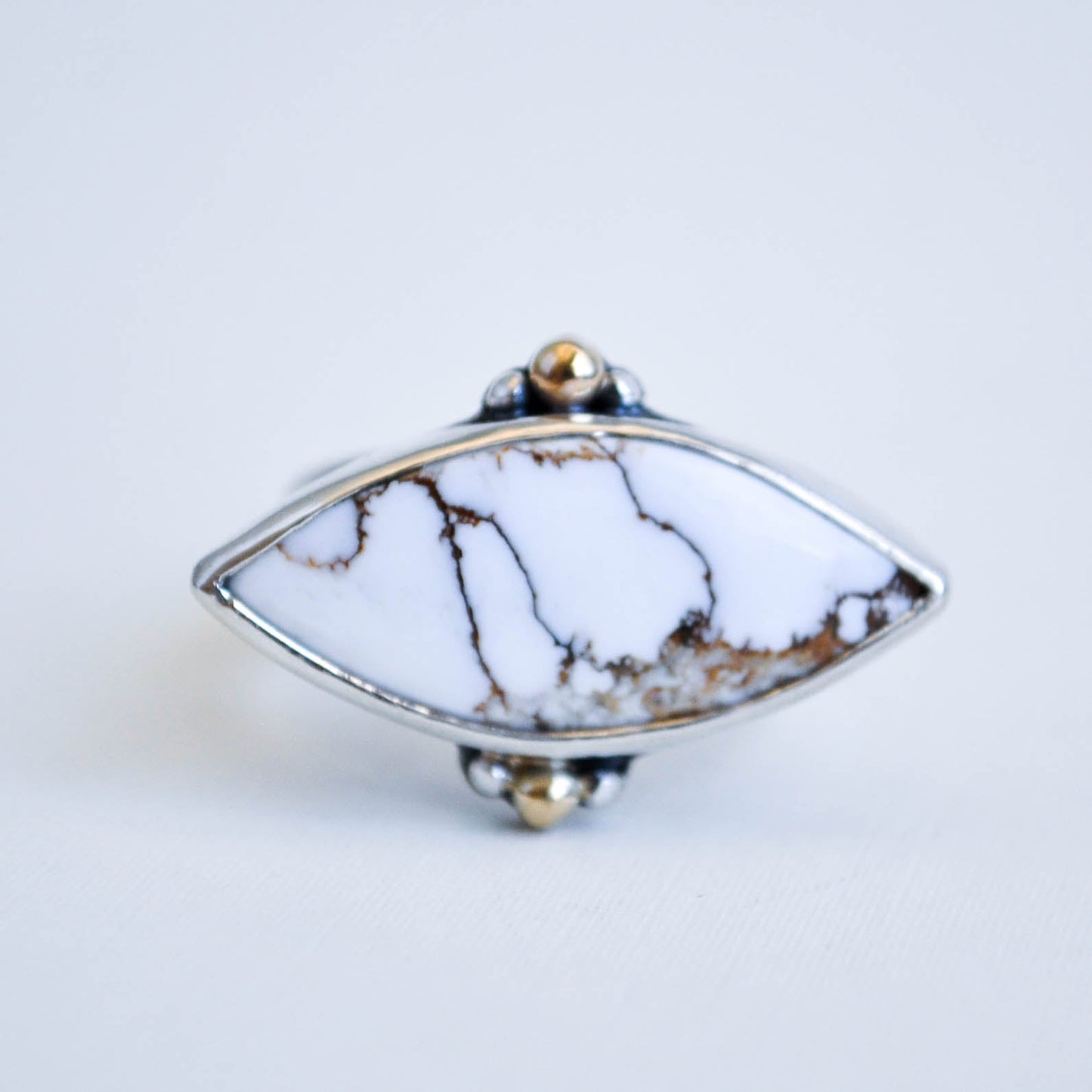 Marquise shaped gemstone ring with marble pattern on a white background