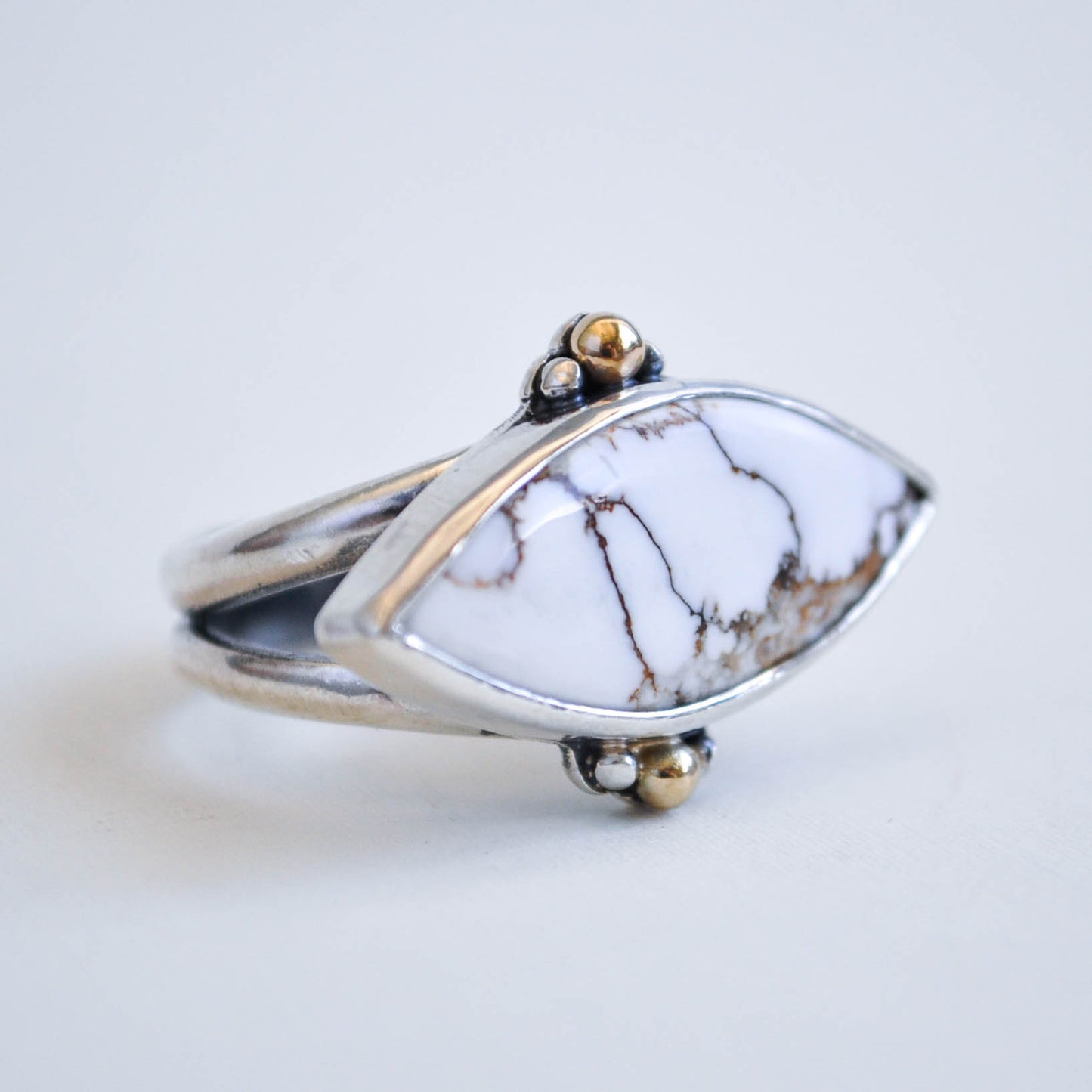 Ring with a white stone and gold accents on a light background