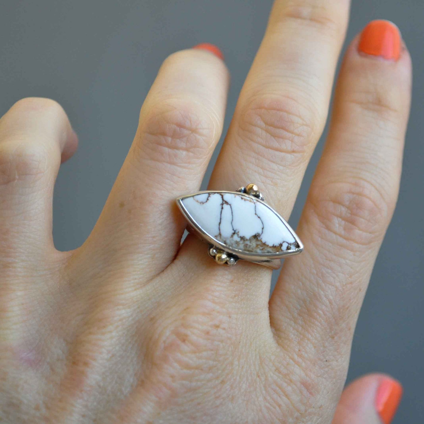 Close-up of a hand wearing a ring with a stone on a gray background