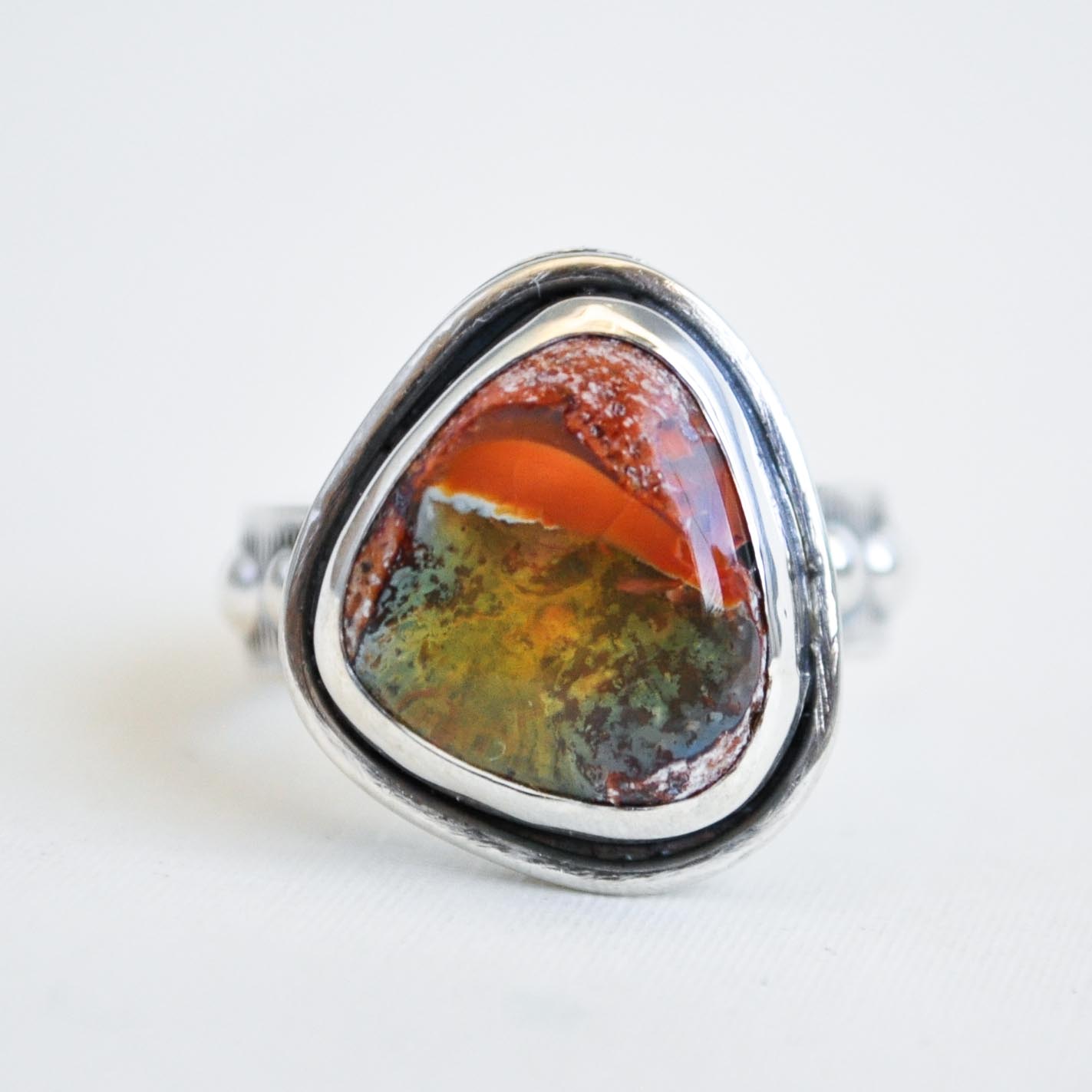 Silver ring with a colorful stone on a white background