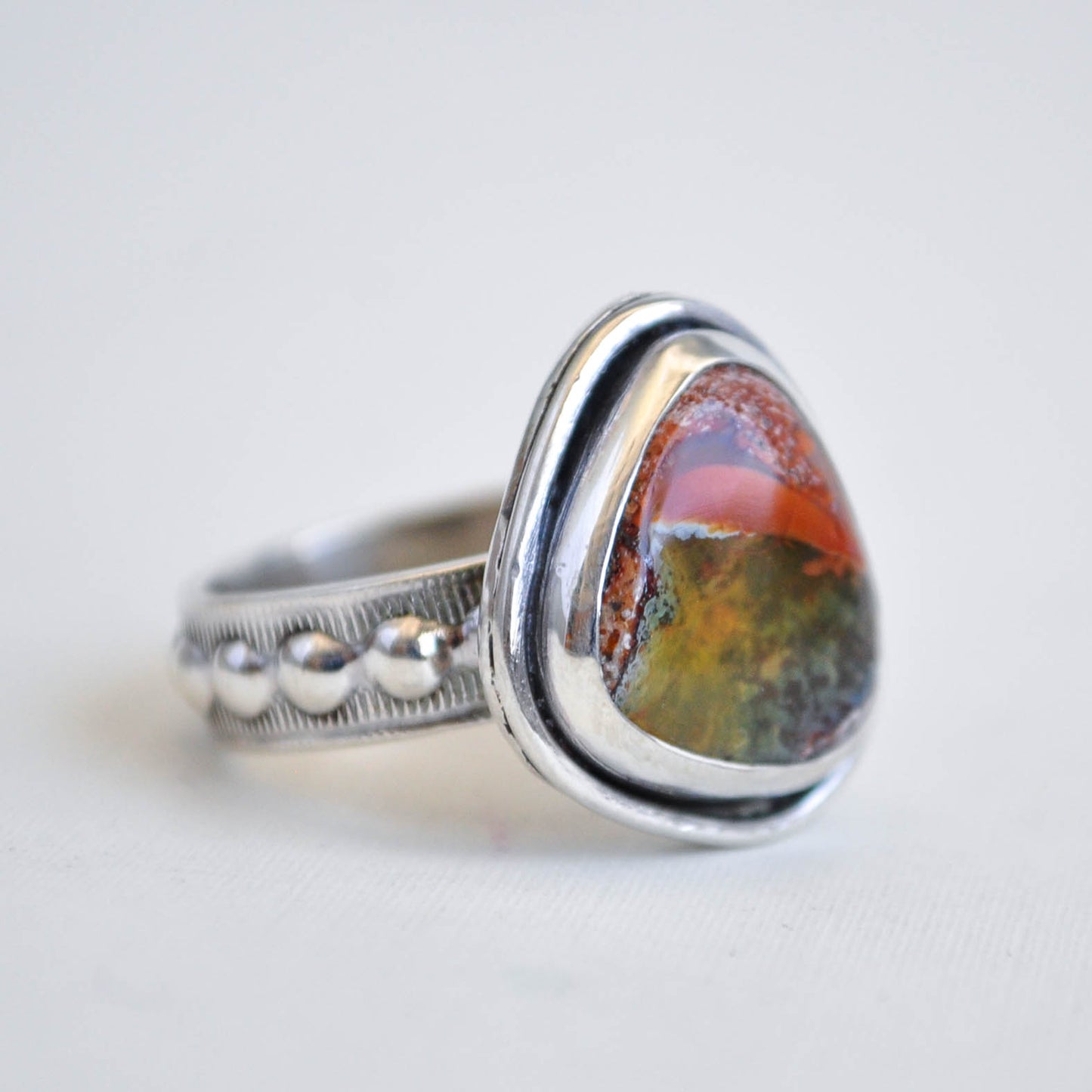 Silver ring with a colorful stone on a white background