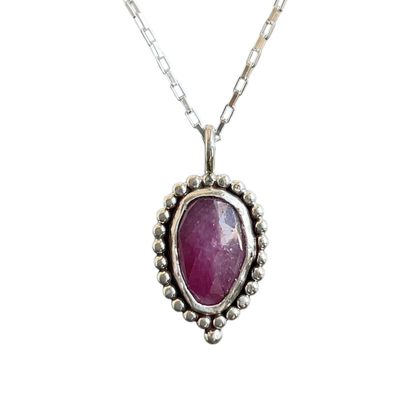 Silver pendant with a purple gemstone on a white background