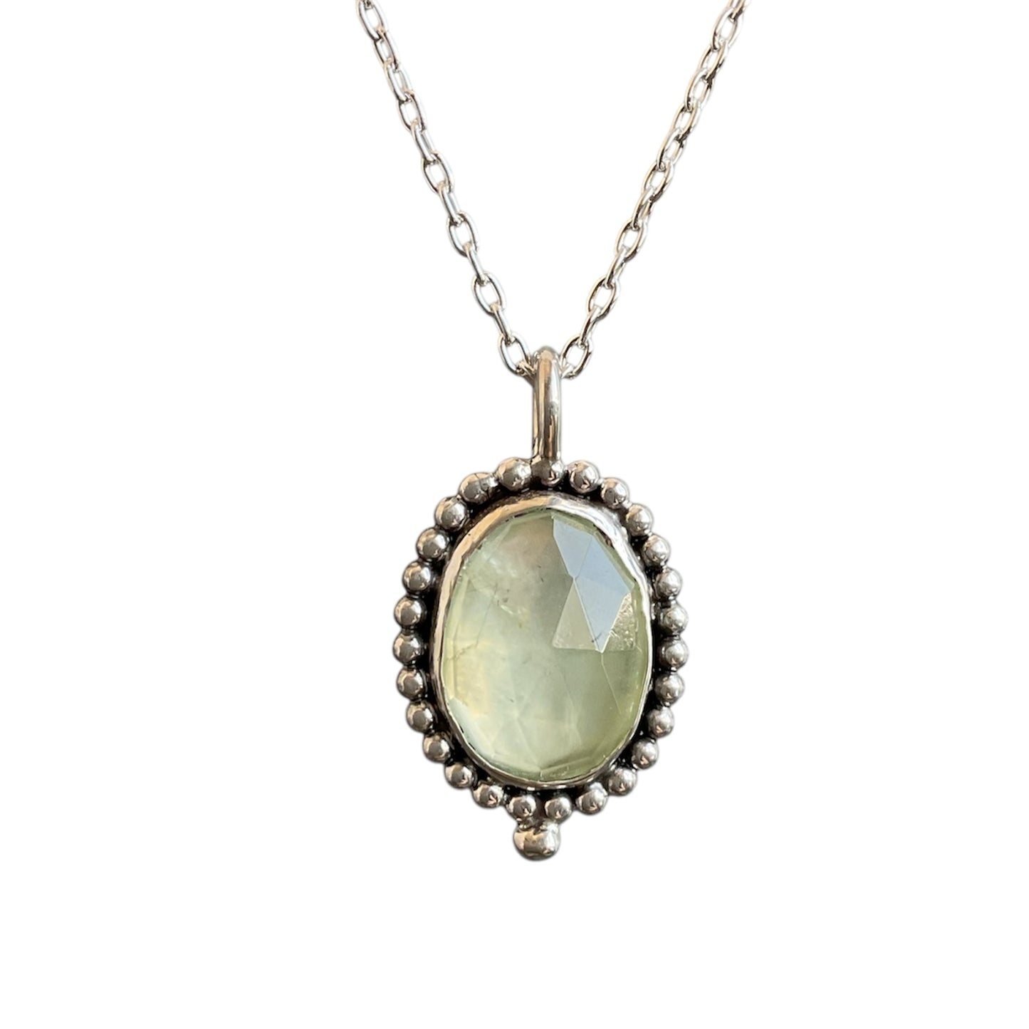 Necklace with a pendant featuring a green gemstone on a white background