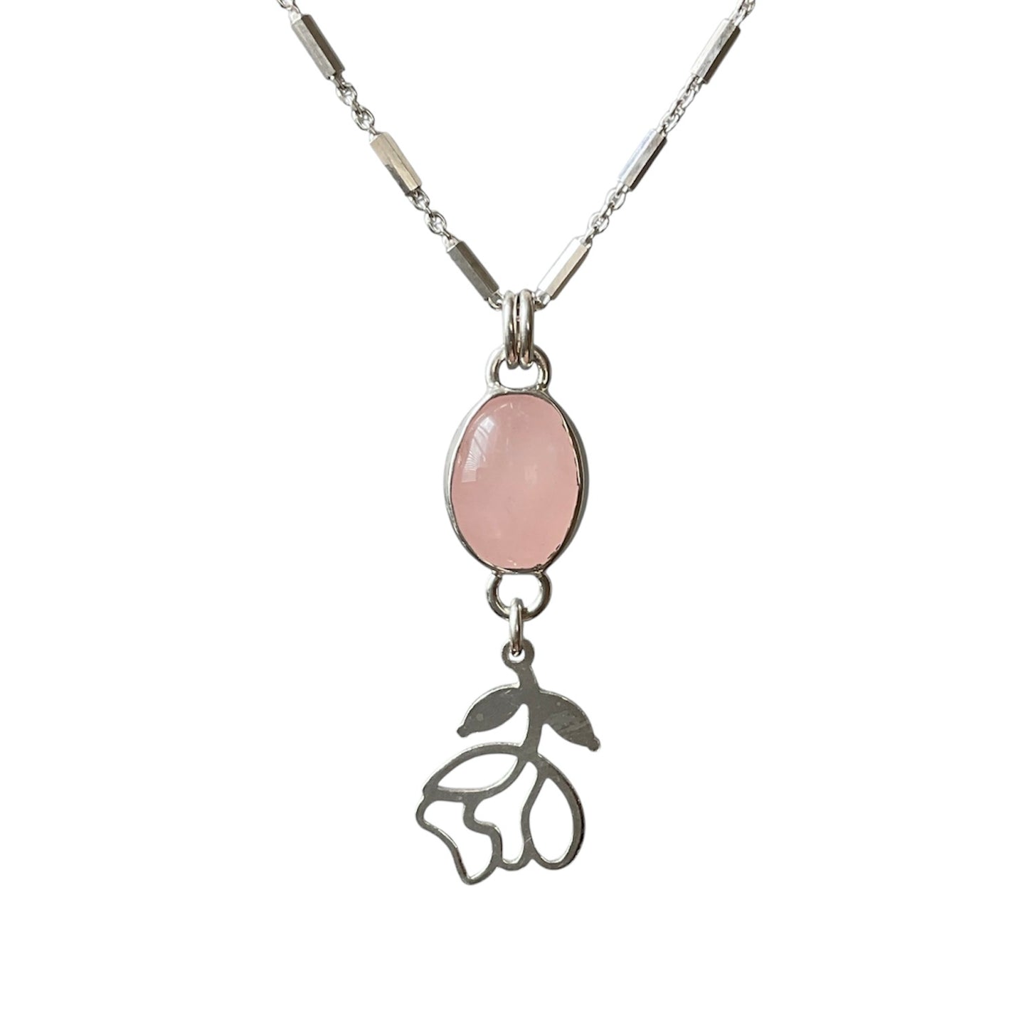 Necklace with a pink stone pendant and floral charm on a white background
