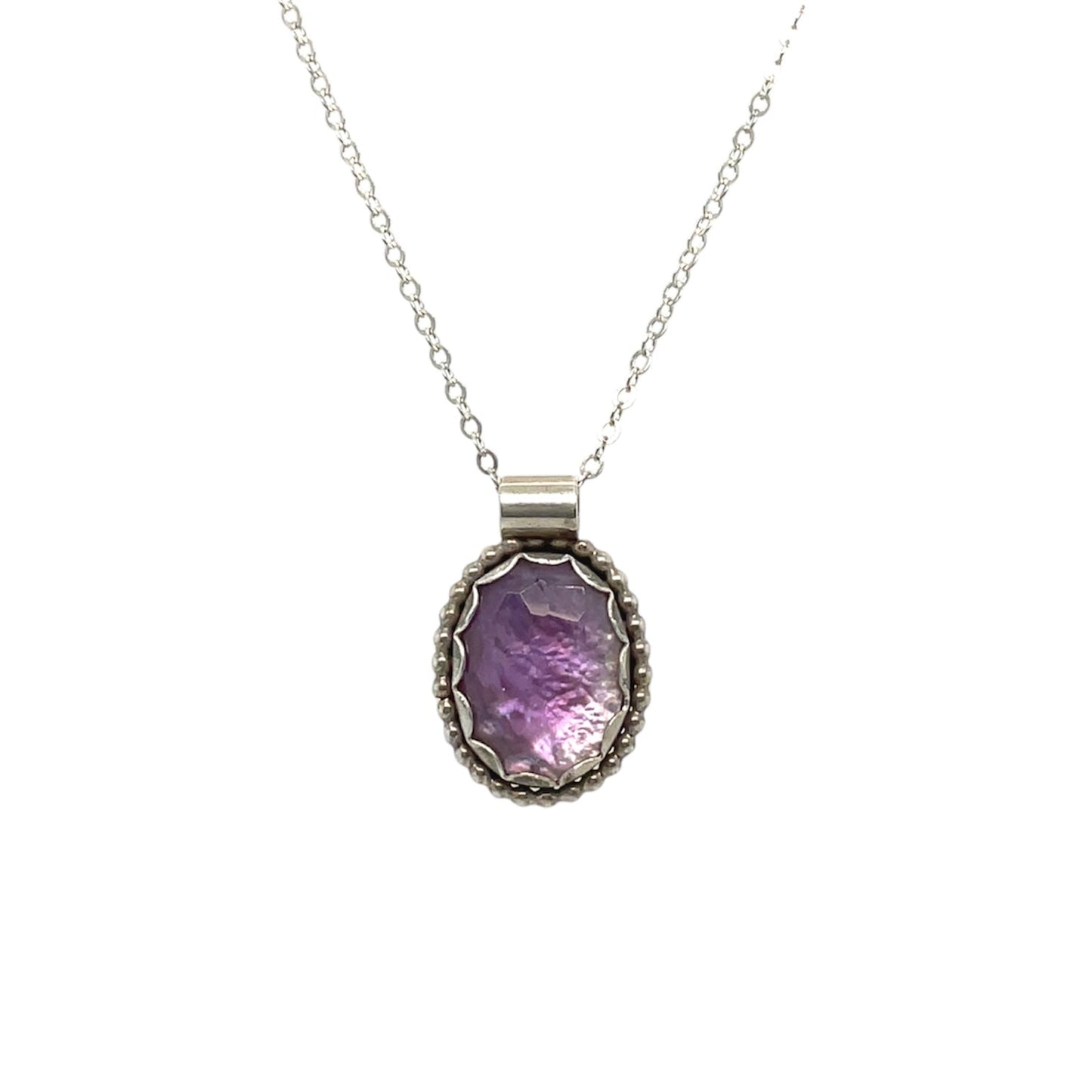 A shimmering semitransparent purple amethyst pendant set in sterling silver with a graceful beaded border and cable chain.