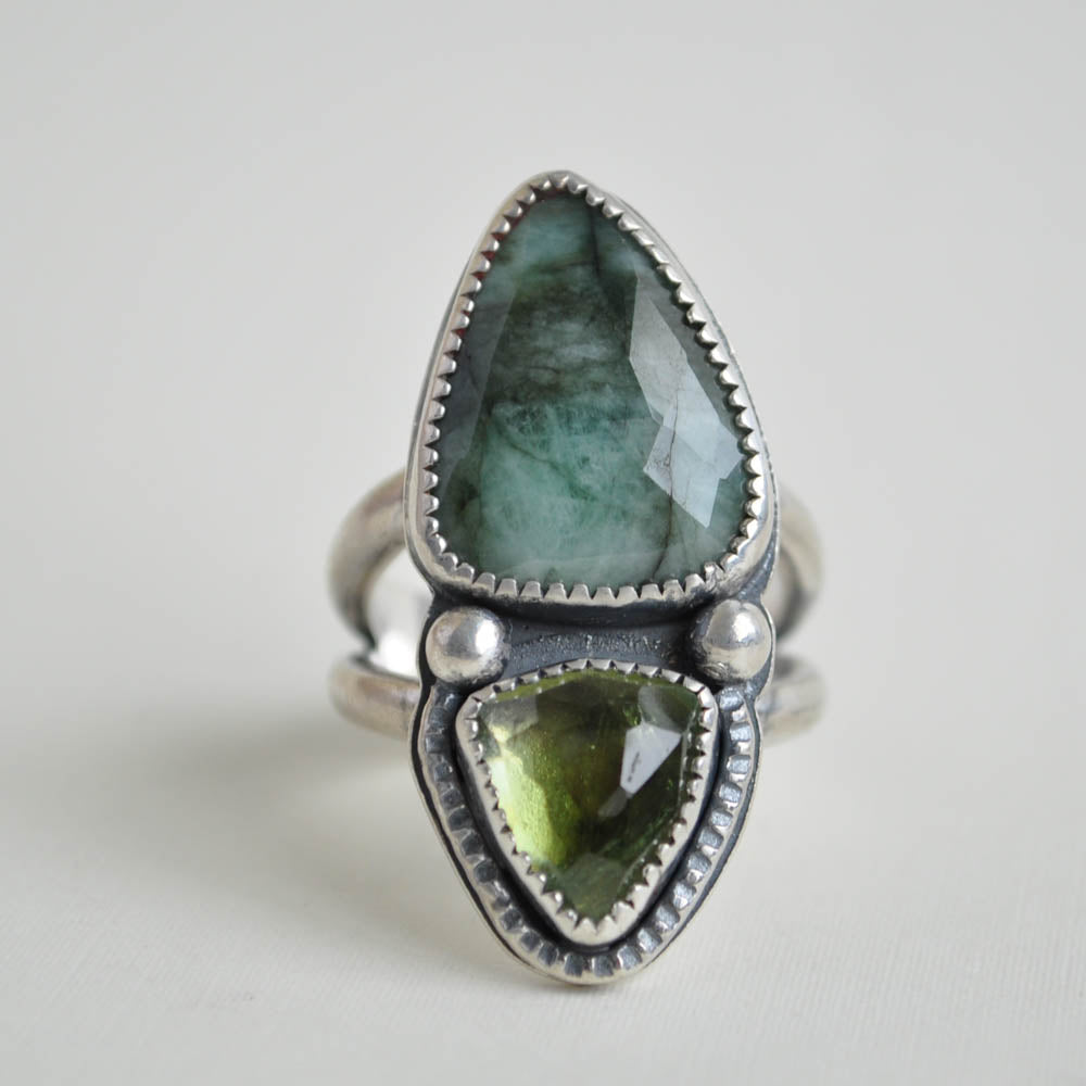 Double stone ring with emerald and green tourmaline with a split band and textured border.