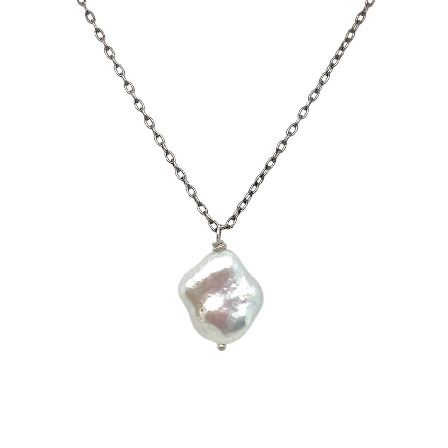 A large, white, irregularly-shaped freshwater pearl pendant hangs on an oxidized sterling silver chain.