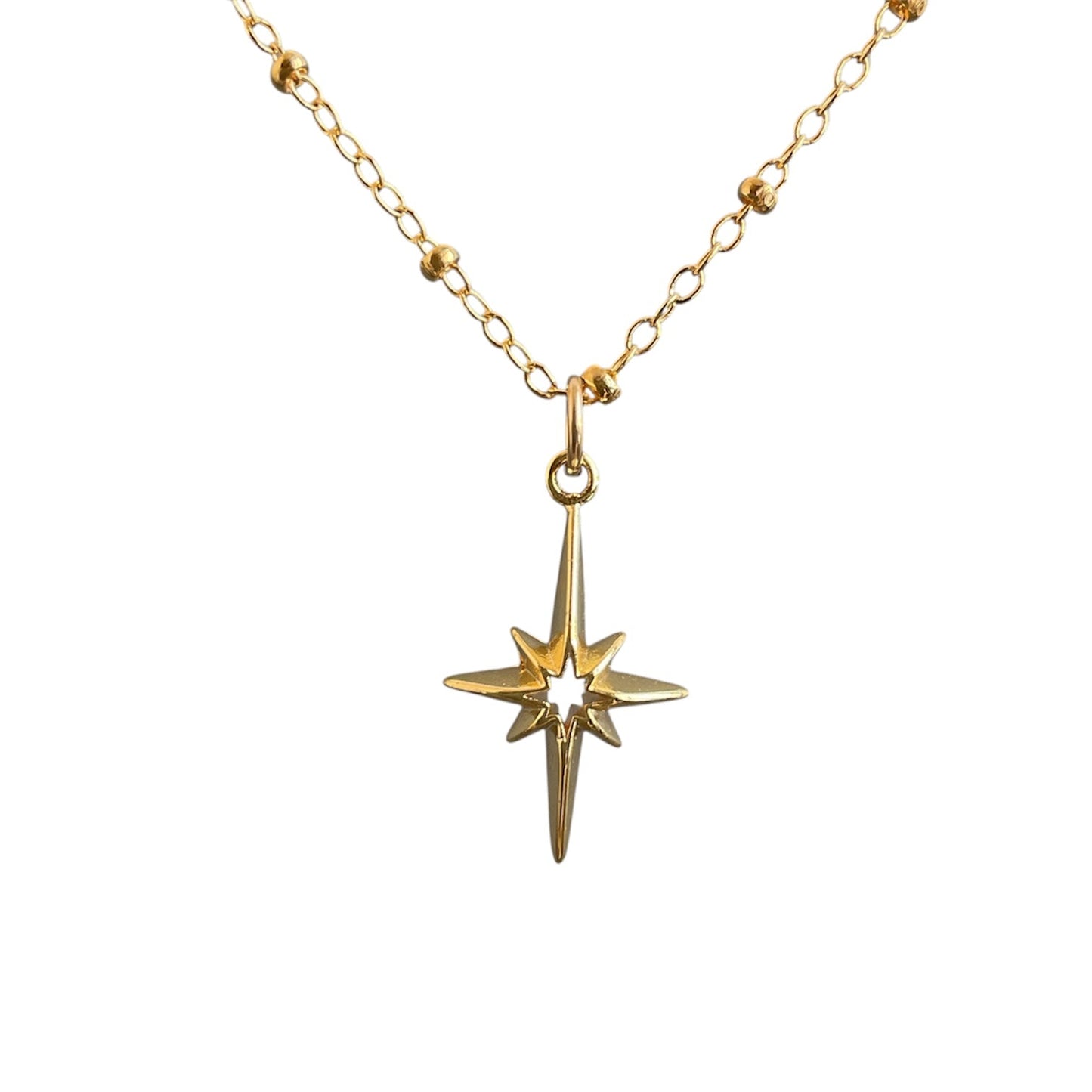 Gold necklace with a star-shaped pendant on a white background