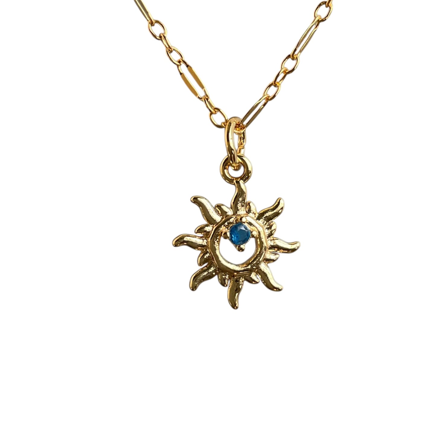 Gold necklace with sun-shaped pendant featuring a blue gemstone on a white background