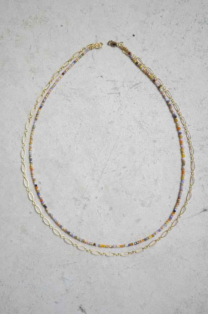 Necklace with multicolored beads and gold chain on a gray surface