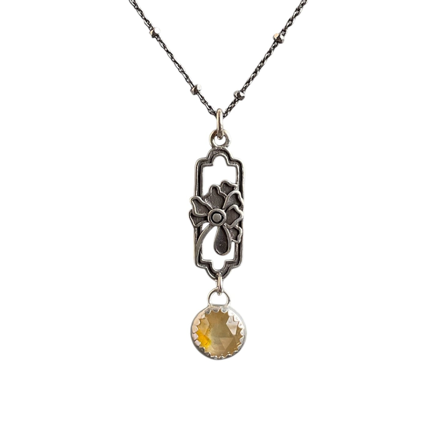 A vibrant yellow sapphire stone set and hung under an open flower frame. Solid sterling silver setting and chain.