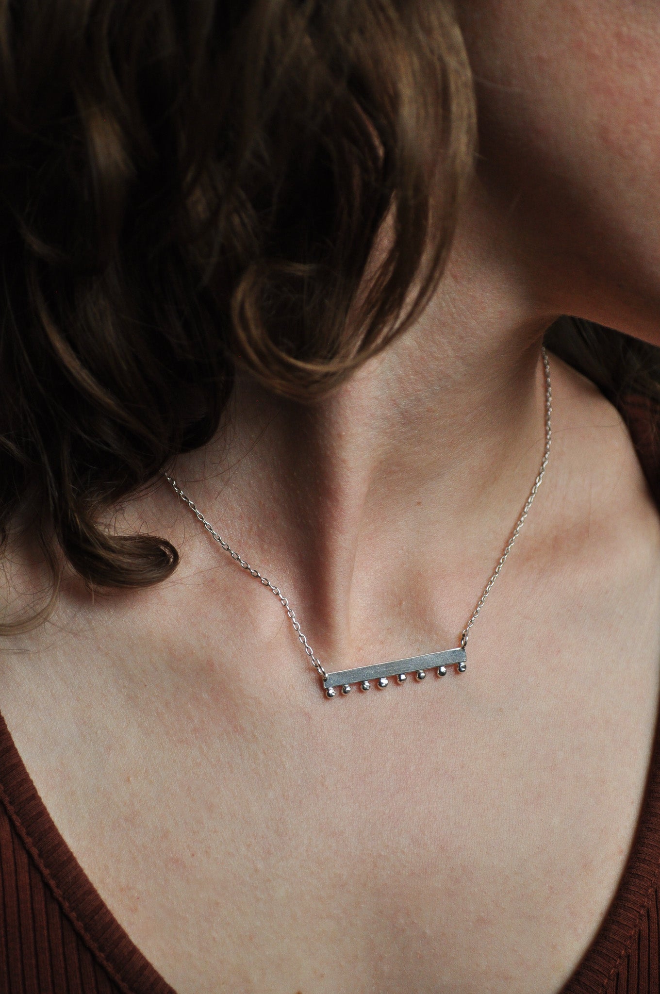 Necklace with a small rectangular pendant on a person's neck