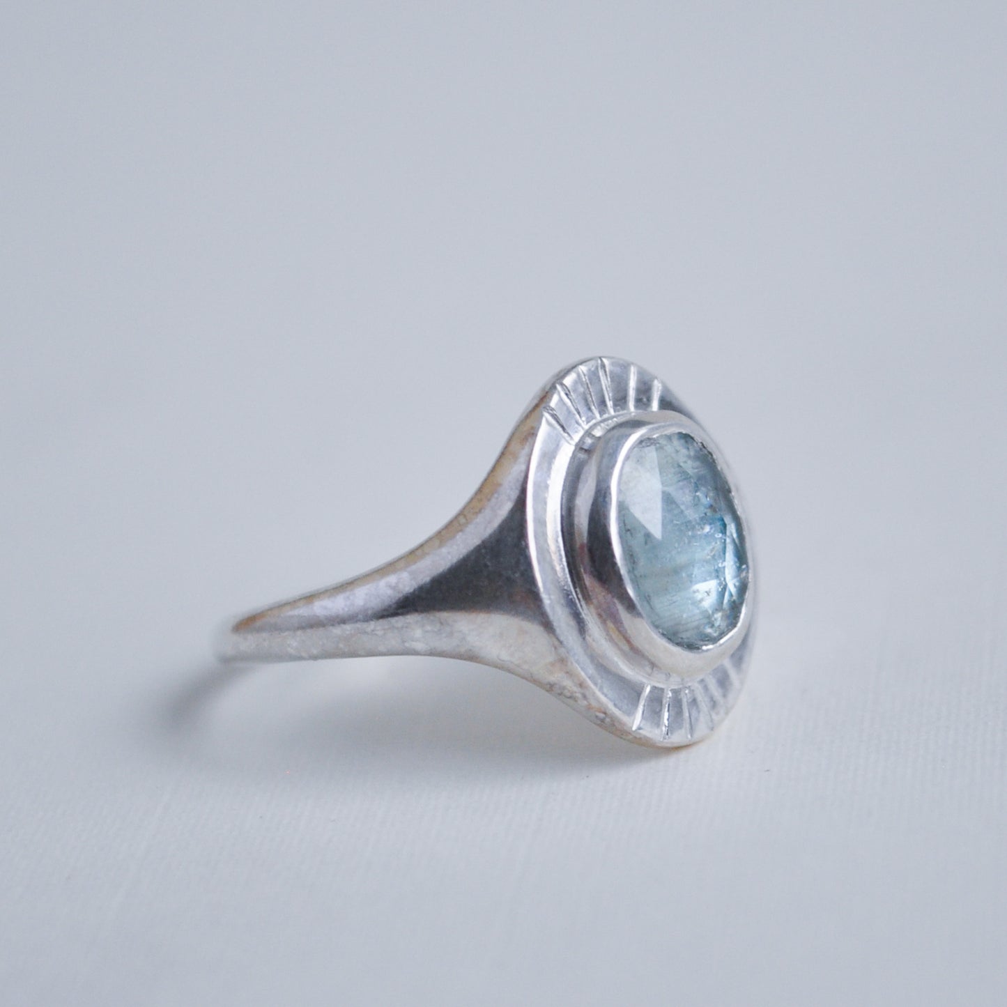 Silver ring with a blue gemstone on a light gray background