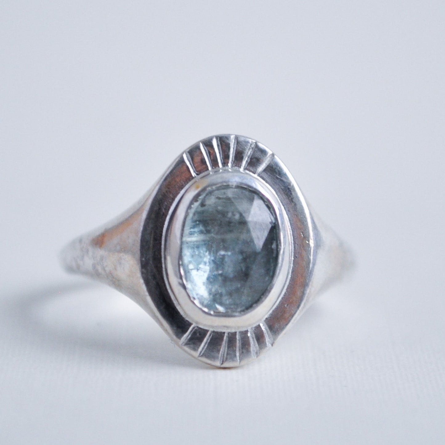 Silver ring with a blue gemstone on a light gray background