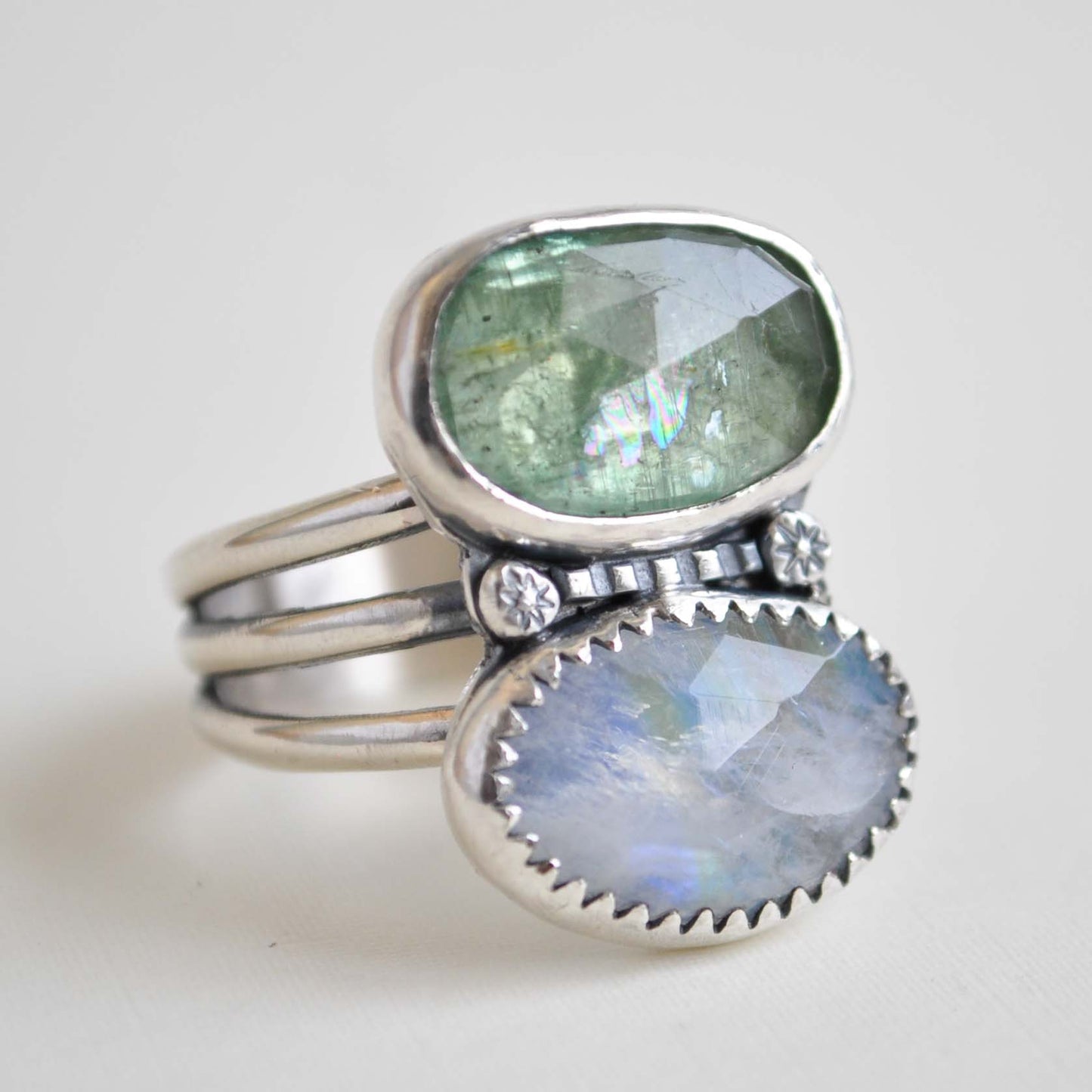 Silver ring with two gemstones on a light gray background