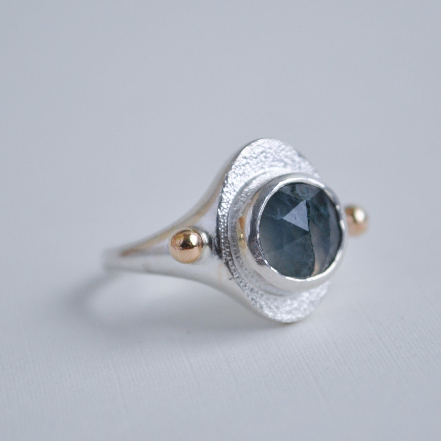Silver ring with a green moss quartz gemstone on a gray background