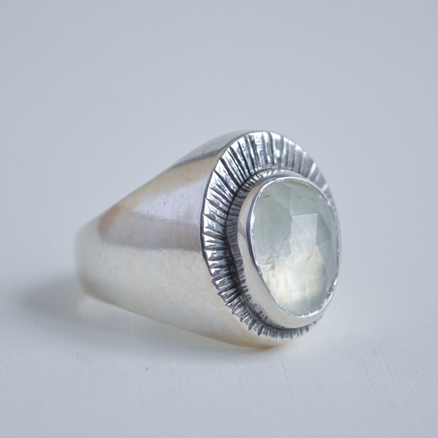 Silver ring with a light green stone on a light gray background