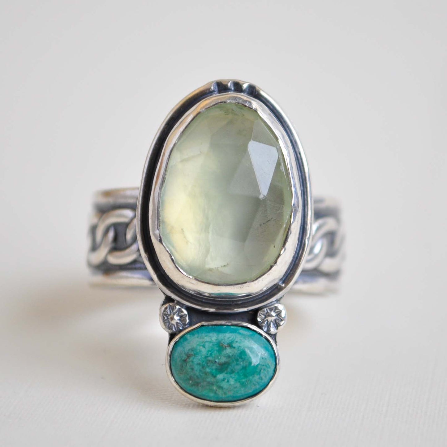 Silver ring with green and blue stone on a white background