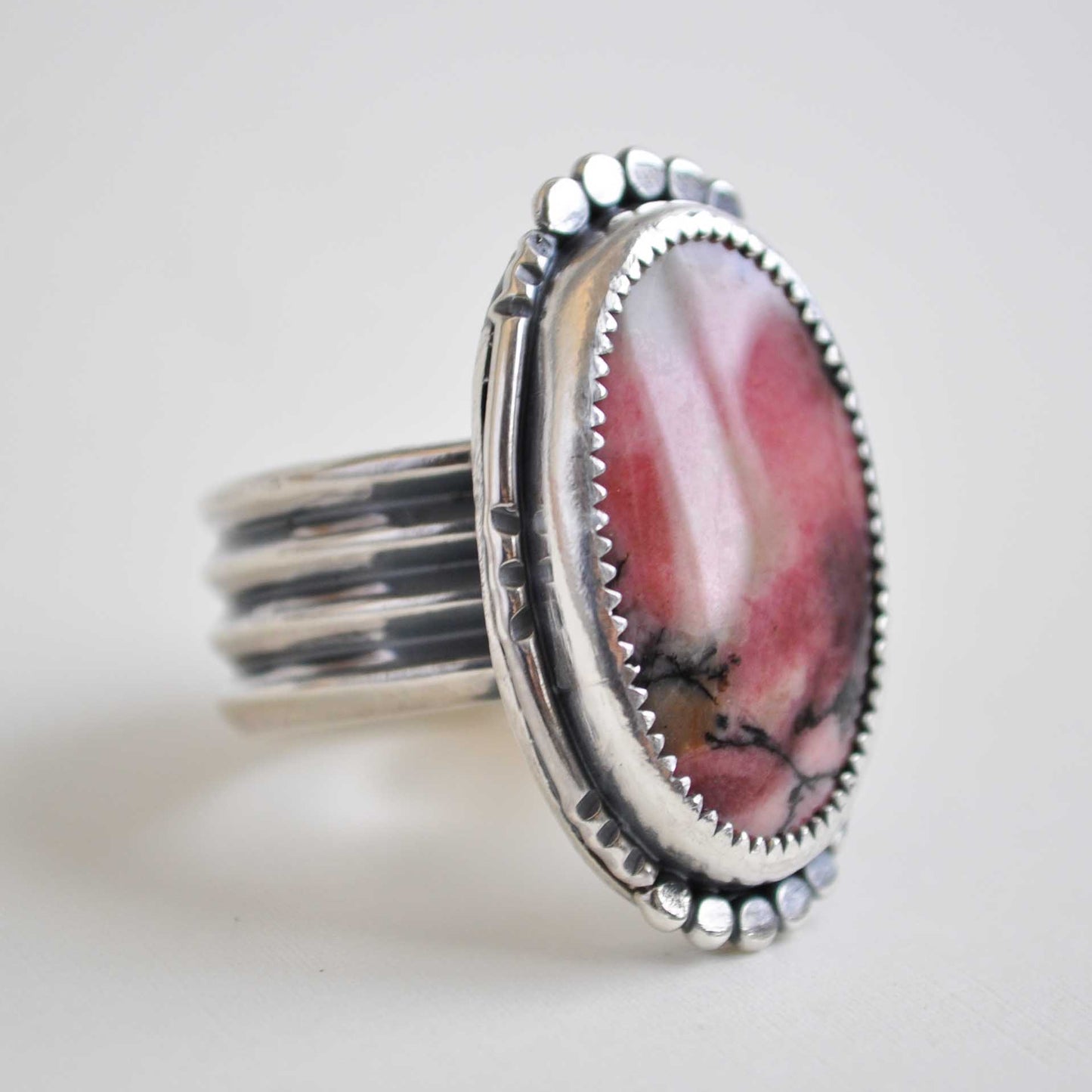 Silver ring with a pink stone on a light gray background