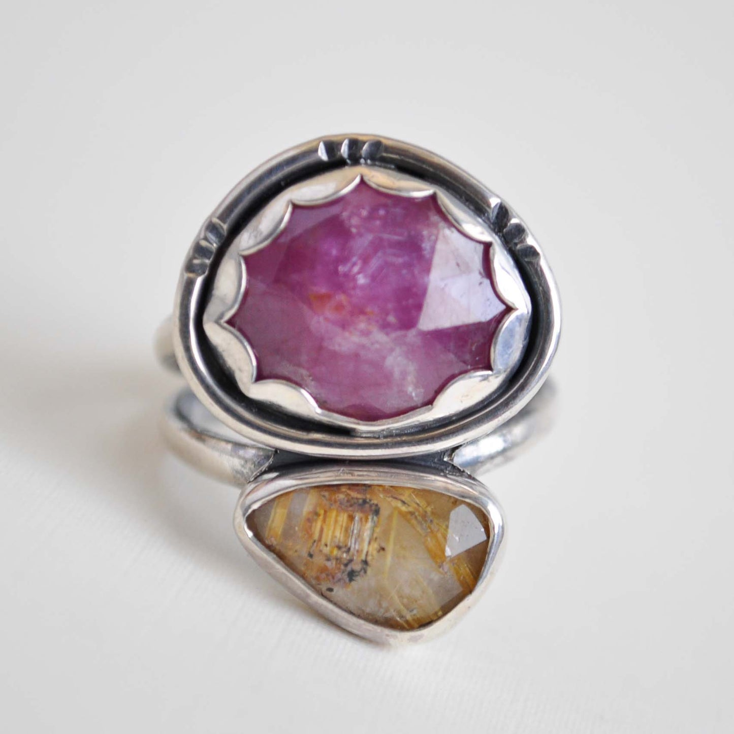 Silver ring with pink and yellow gemstones on a white background