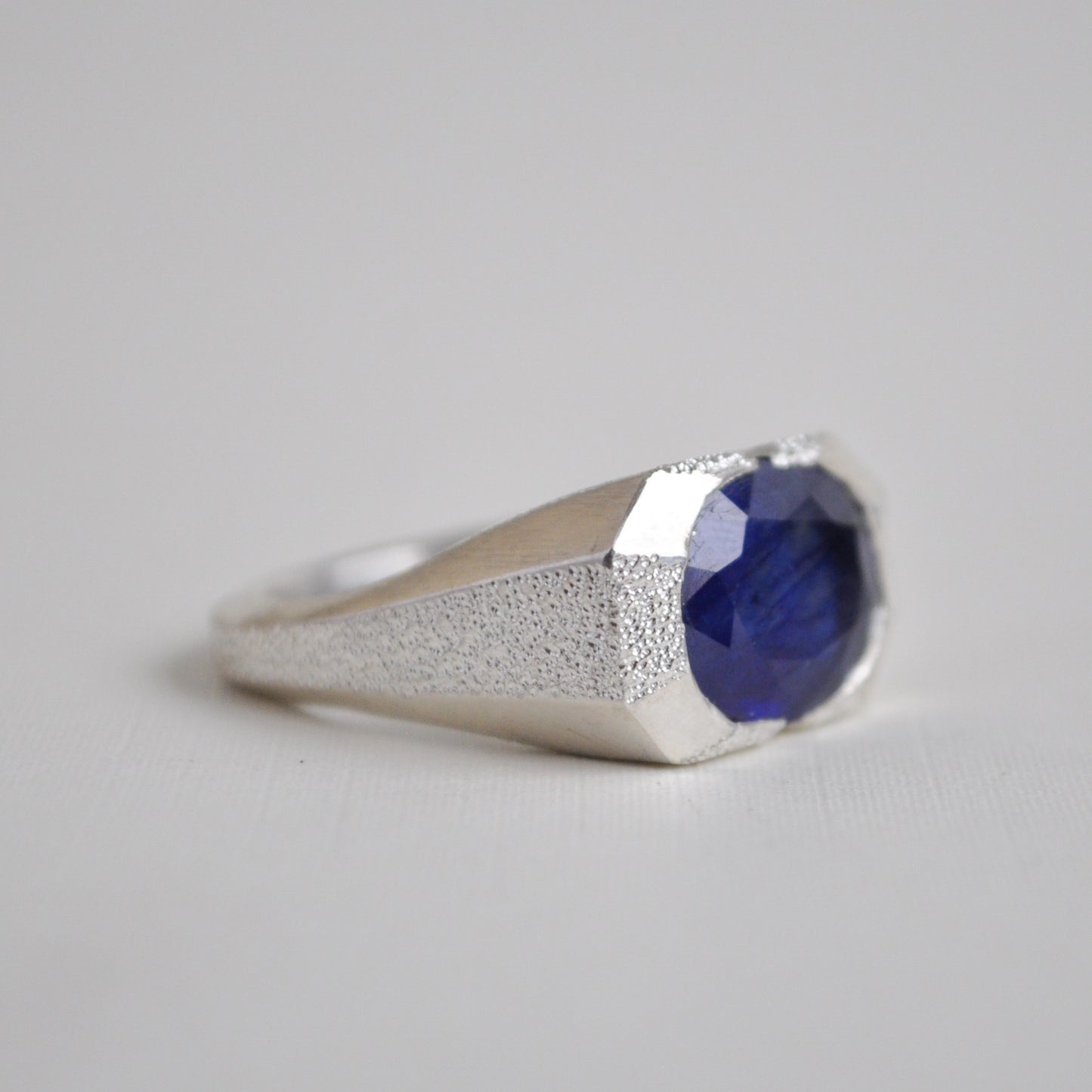 Silver ring with a blue gemstone on a light gray background