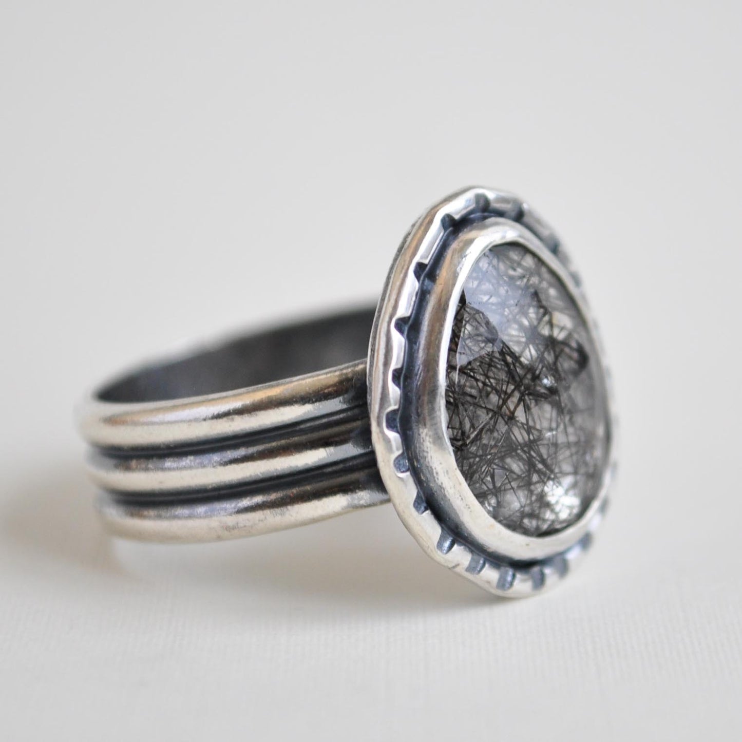 Silver ring with textured band on a light gray background