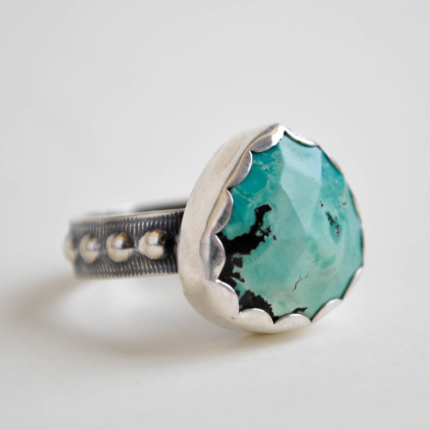 Ring with turquoise stone and silver band on a light background