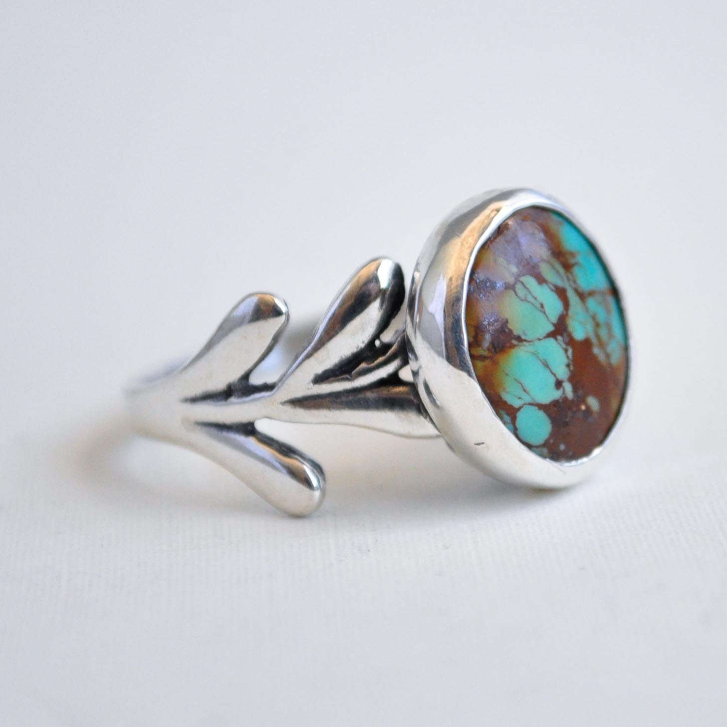 Silver ring with a colorful stone on a light gray background