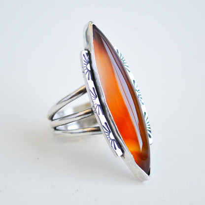 Silver ring with a large orange stone on a white background