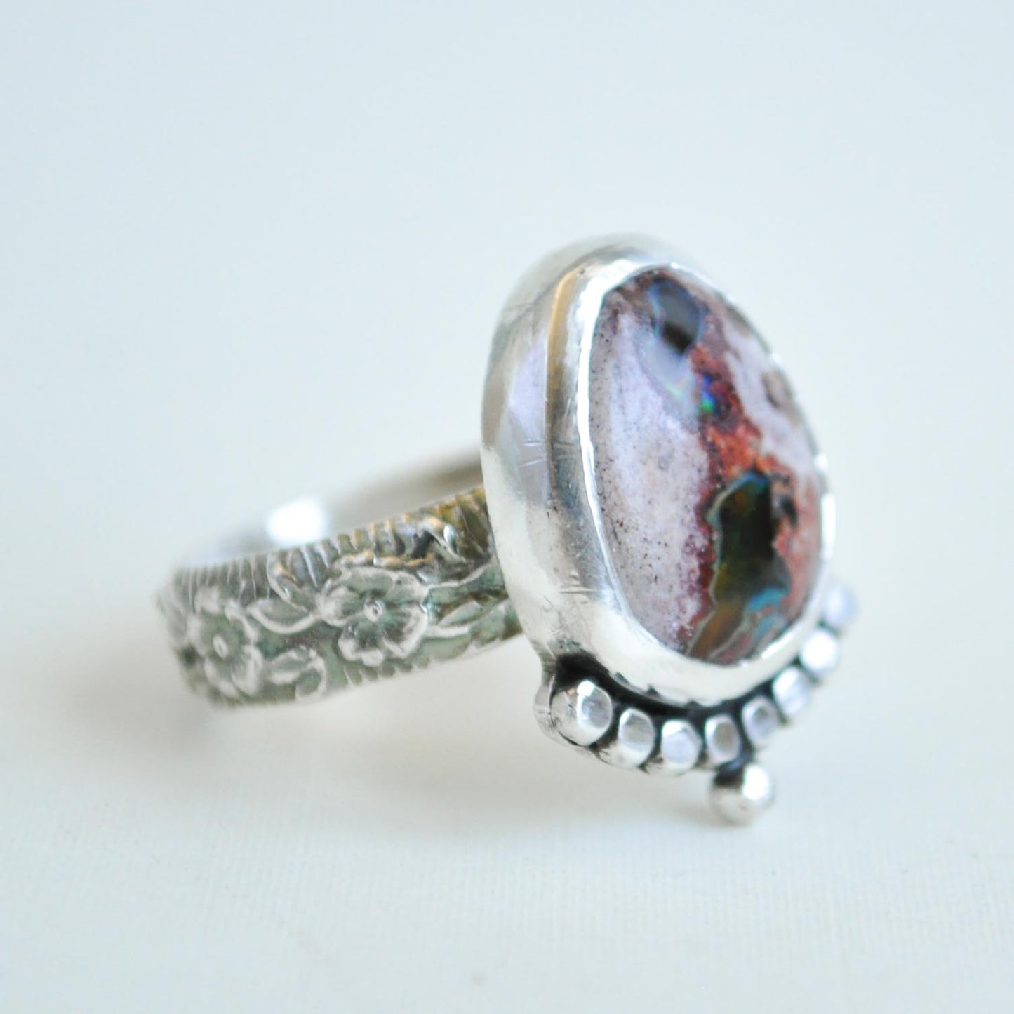 Silver ring with a colorful stone on a light background