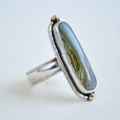 Silver ring with a large green stone on a light gray background
