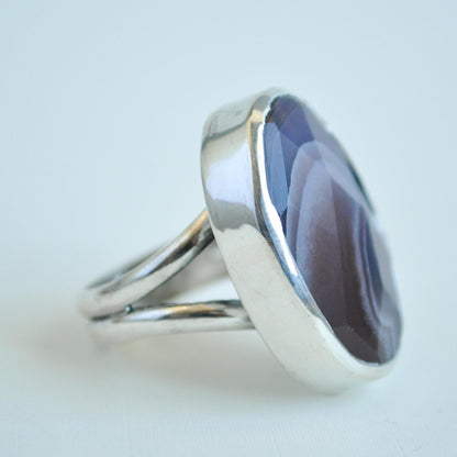 Silver ring with a purple stone on a light gray background