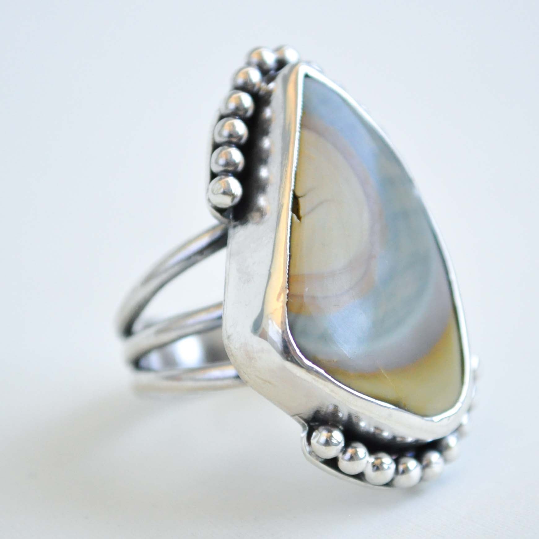 Silver ring with a teardrop-shaped stone on a light gray background