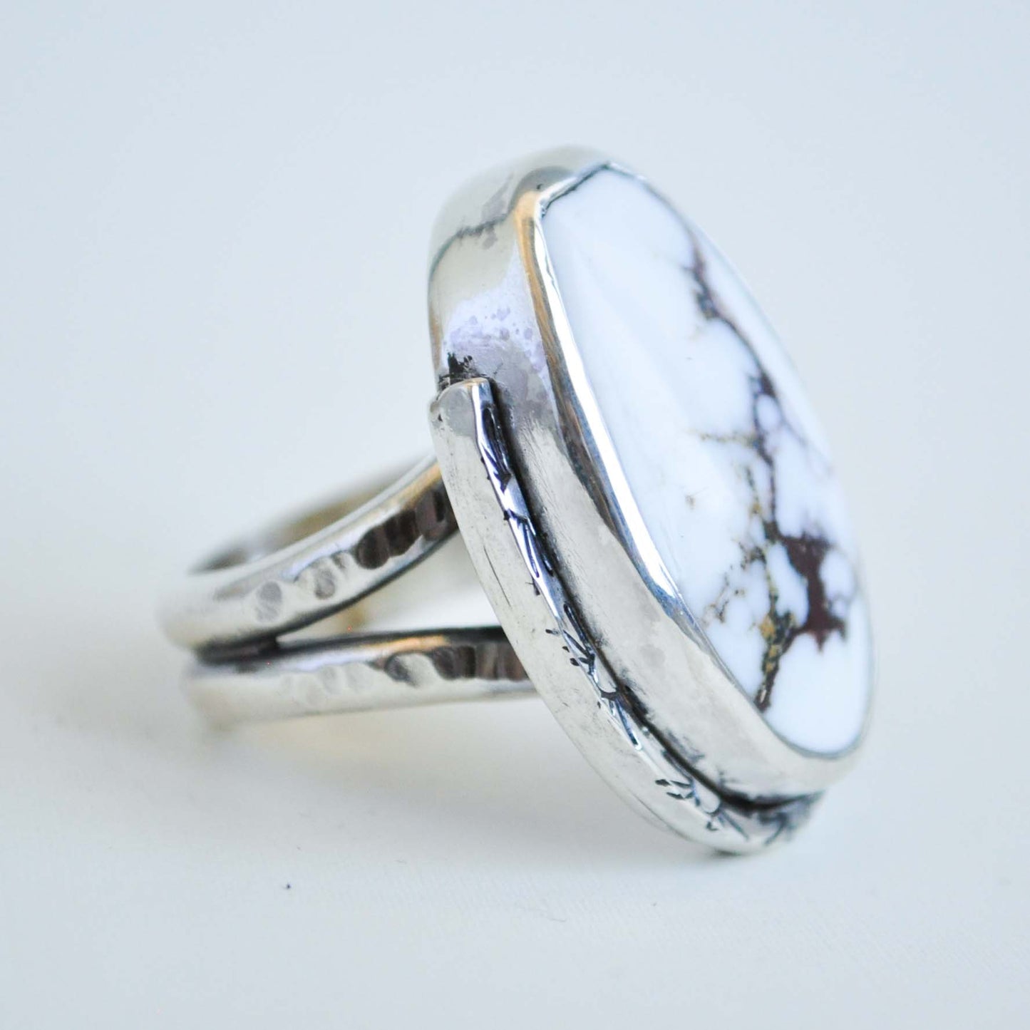 Silver ring with a white marbled stone on a light gray background