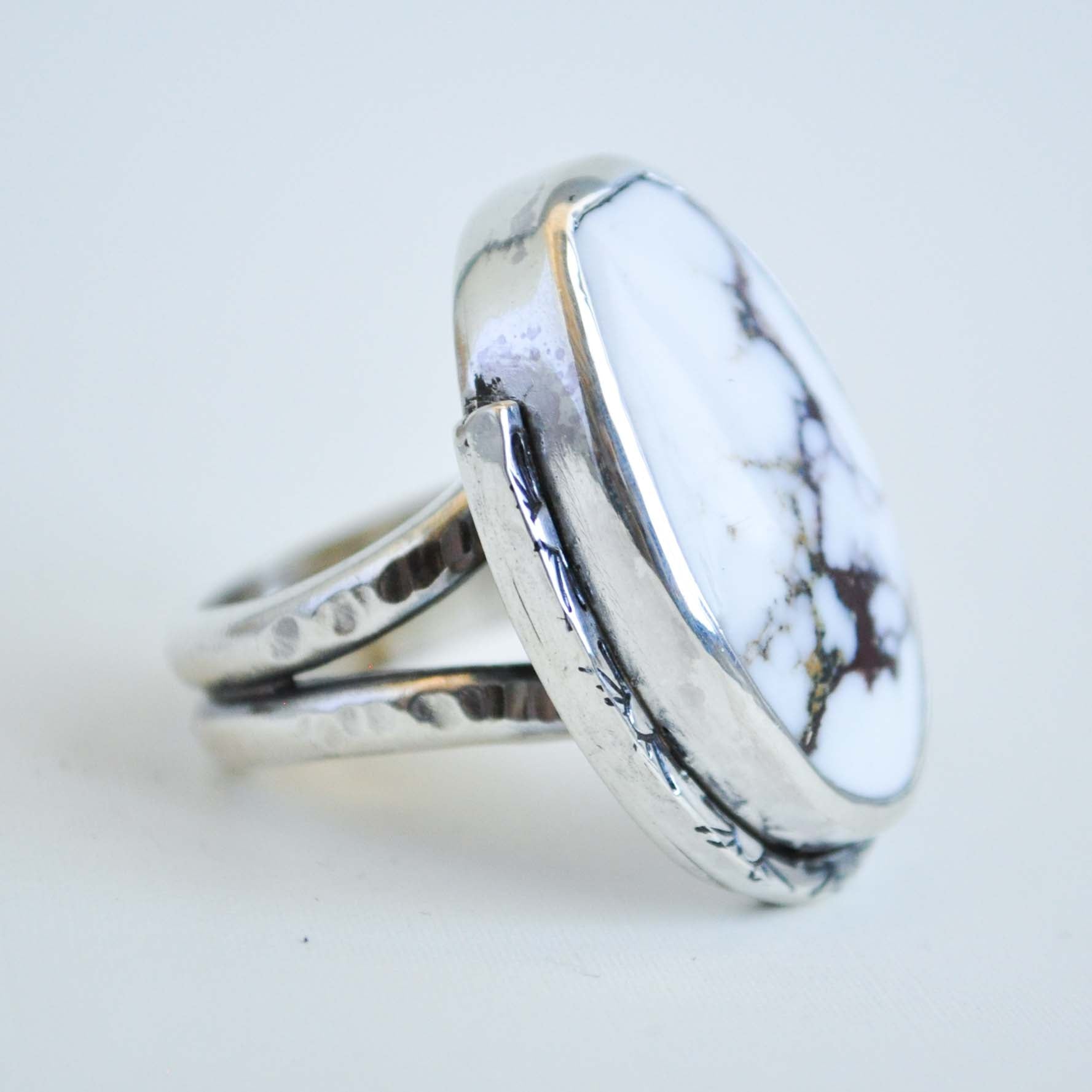 Silver ring with a white marbled stone on a light gray background