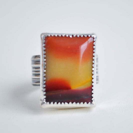 Yellow to red color fade in a square jasper gemstone bezel set in a sterling silver setting with a wide ridged ring band. 