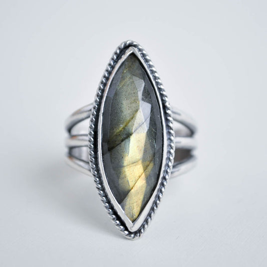 Long marquise shaped labradorite gemstone with a twisted border on a split trio ring band. 