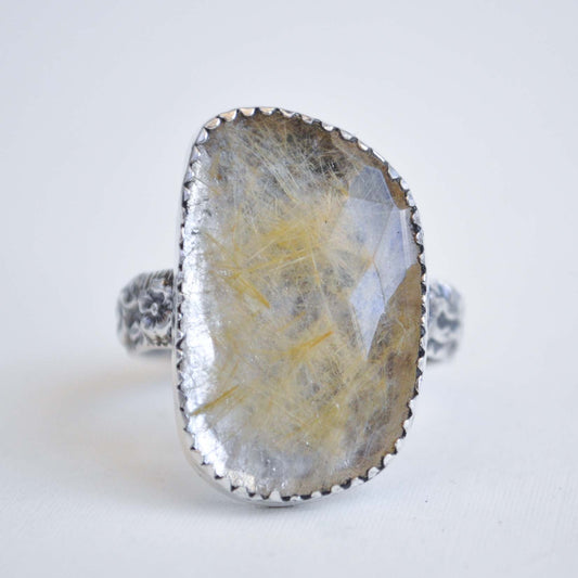 Silver ring with a large, rough-cut gemstone on a white background