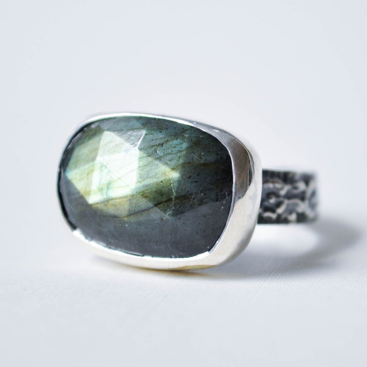 Silver ring with a labradorite stone on a light gray background