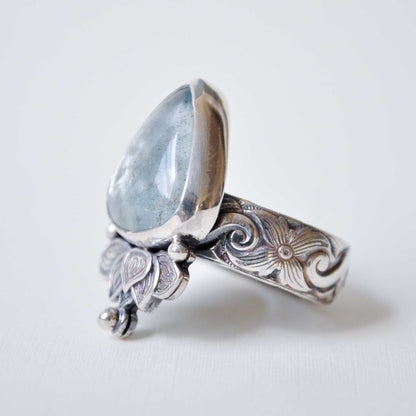 Silver ring with a teardrop-shaped gemstone on a white background