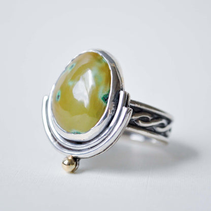 Silver ring with a yellow gemstone on a white background