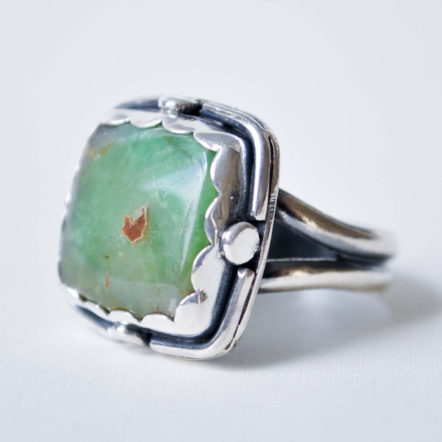Silver ring with a green stone on a white background